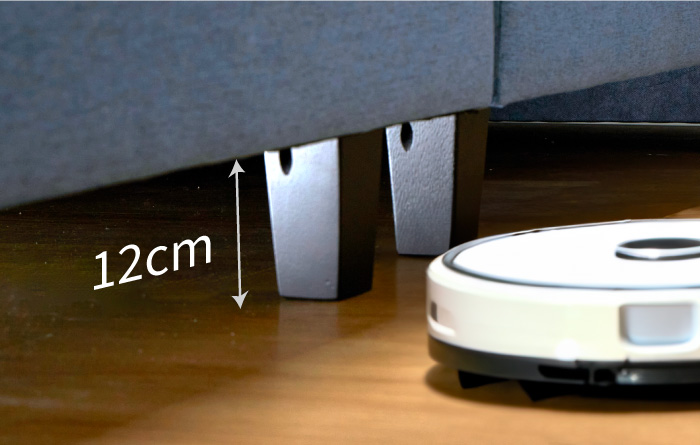 An Image Of A Gap Between The Bed And The Wooden Floor With The Measurement Of 12cm And A Robot Vacuum Cleaner At The Side  - Coway Prime Lite Series