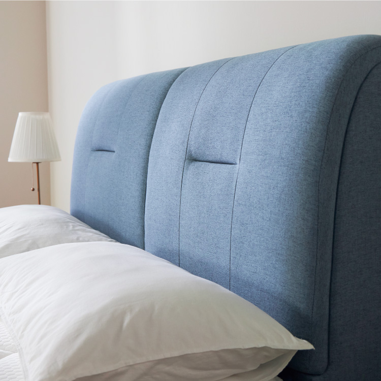 Blue Bedframe Against The Wall With Two Pillows Against It And A Lamp On The Side - Coway Prime Lite Series
